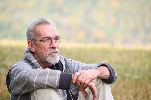 Elderly man sat outside in a meadow